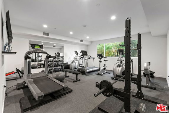 Indoor gym area with exercise equipment, including treadmills and weights.