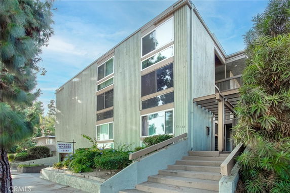 Front view of a three-story building with a staircase leading to the entrance.