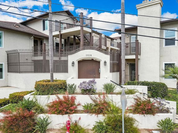 Front view of a multi-story residential building with balconies and gated entrance.