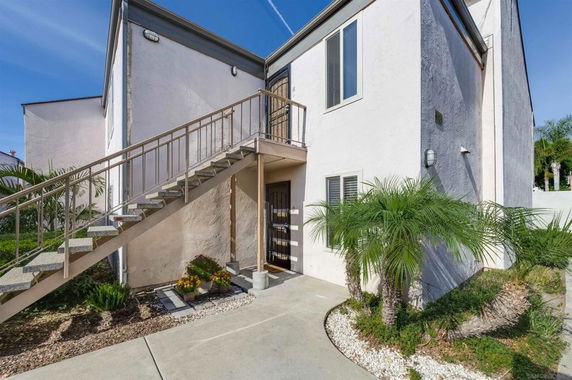 Front view of a two-story house with an exterior staircase leading to the upper level.