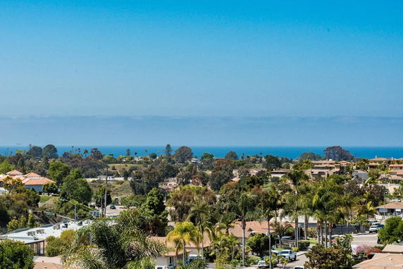 Expansive view of a residential area with ocean in the background under a clear blue sky.