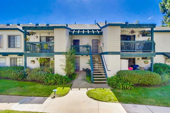 Front view of a two-story residential building with multiple balconies and outdoor stairs.