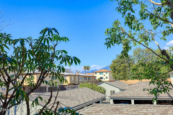 View of neighboring buildings and trees with clear blue sky.