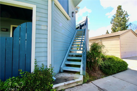 Front view of a house with an external staircase leading to the upper floor.