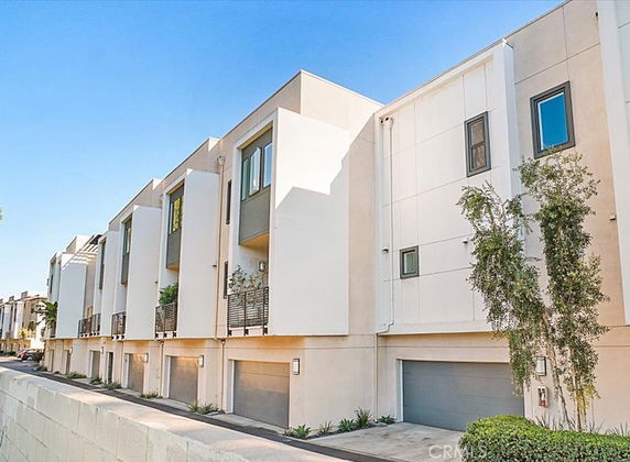Front view of modern multi-story townhouse buildings with garage doors at ground level.
