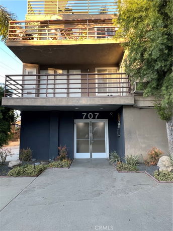 Front view of a multi-story building with balconies and a ground-level entrance.