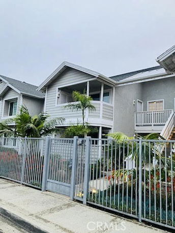 Front view of a two-story house with a white balcony and fenced yard.