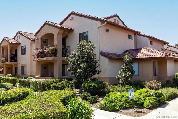 Front view of a multi-story residential building with balconies and tiled roofs.