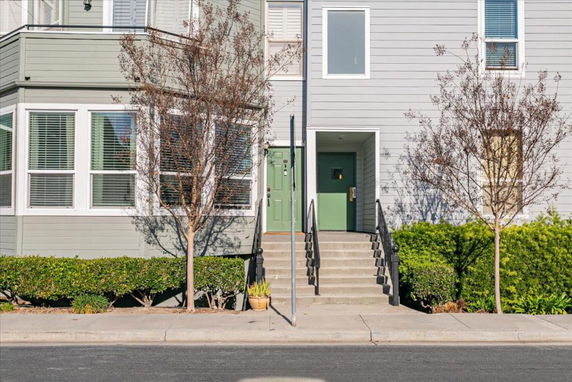 Front view of a modern two-story building with a staircase leading to a green door.