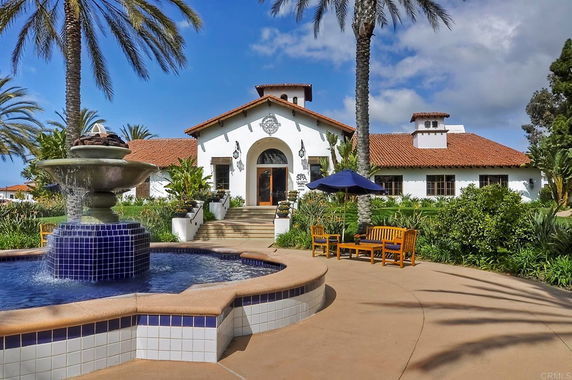 Front view of a building with red tile roof and fountain in foreground.