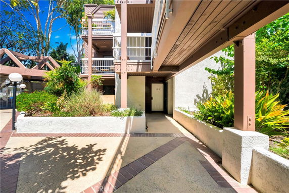 Exterior view of a multi-level building entrance with balconies and surrounding greenery.
