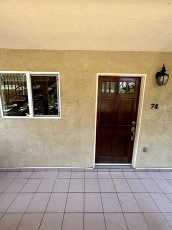 Front view of a house with a wooden door and adjacent window.