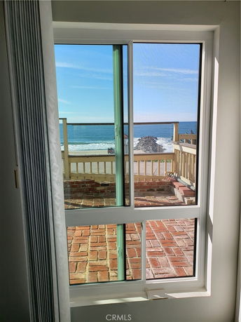 View of the sea and horizon from a window with a balcony in the foreground.