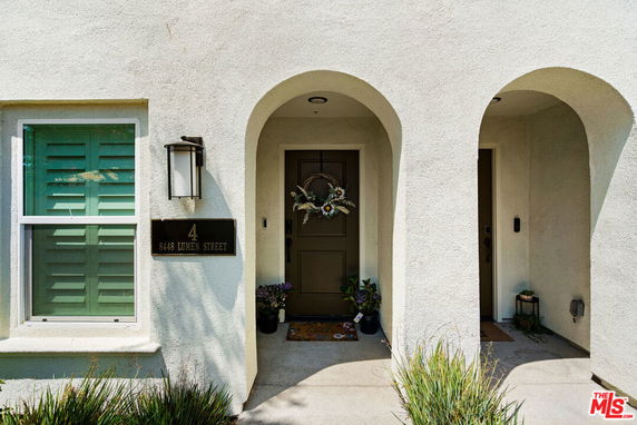 Front view of a house entrance with an arched entryway and a door decorated with a wreath.