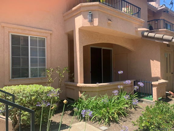 Front view of a house with a small porch and sliding glass door.