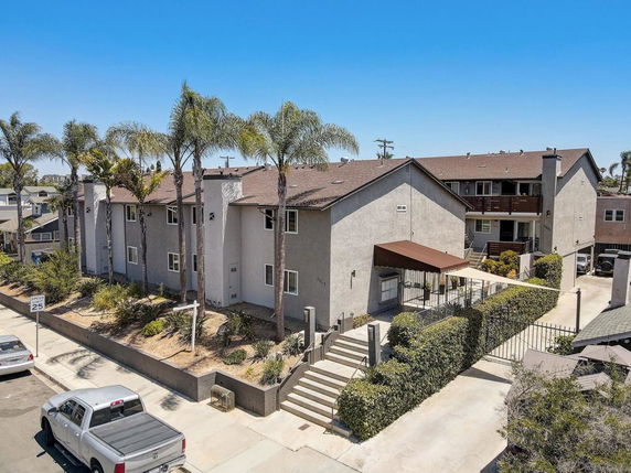 Front view of a multi-story residential building with a gated entrance and canopy.