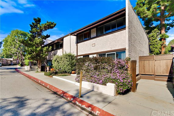 Front view of a two-story residential building with shrubs and trees.