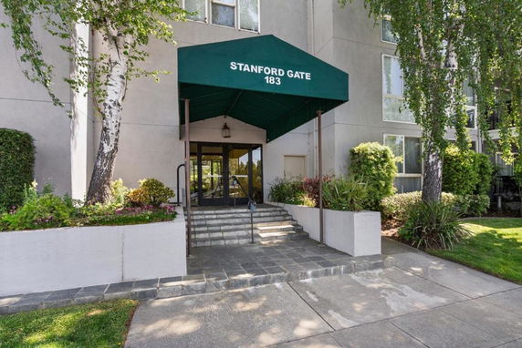 Entrance of a building with a green awning and steps leading to glass doors.