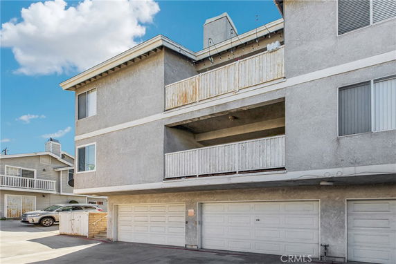 Front view of a multi-story residential building with balconies and garages.