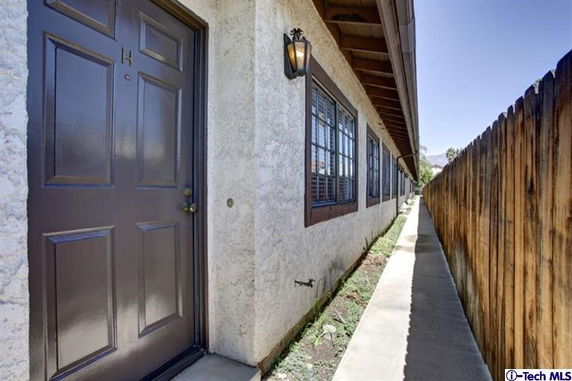 Side view of a building showing a door and windows along a narrow pathway.