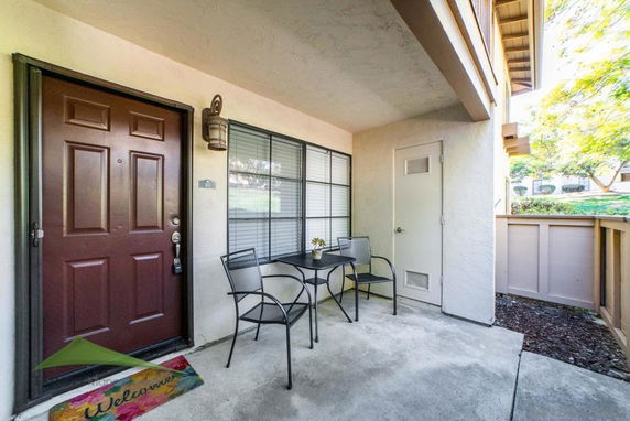 Front view of a house entrance with a small patio area and seating.