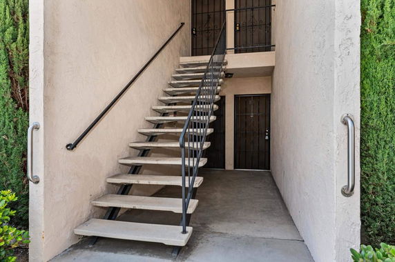 Stairwell leading to the second floor of a two-story building with gated entrances.