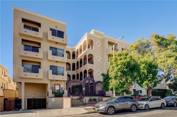Front view of a multi-story building with balconies and arched entrances.
