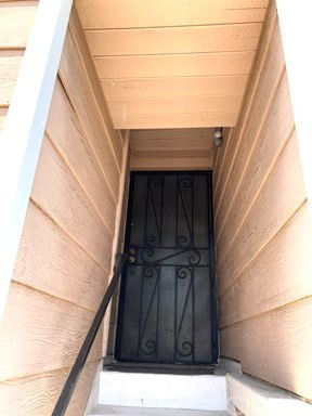 Entrance with wrought iron door and wooden siding.