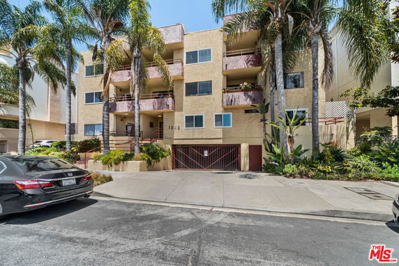 Front view of a three-story apartment building with balconies and a gated entrance.
