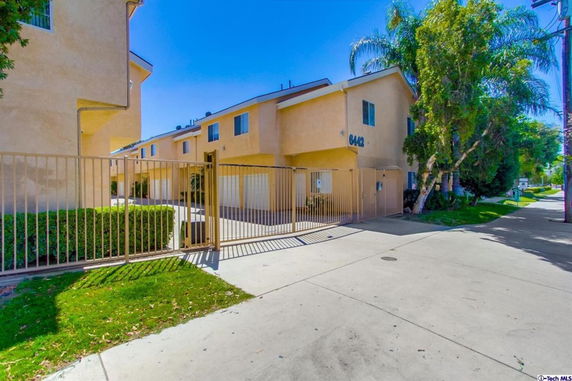 Front view of a residential building with multiple units and a gated entrance.