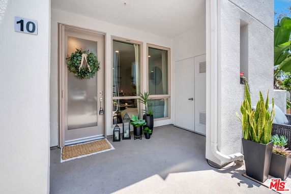 Front entrance of a house with a decorated door and potted plants.