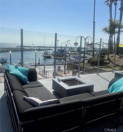 Rooftop seating area with fire pit overlooking a marina and ocean.