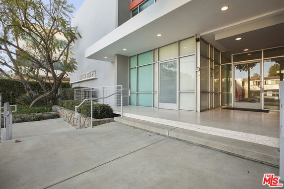 Front view of a modern building entrance with glass doors and windows.