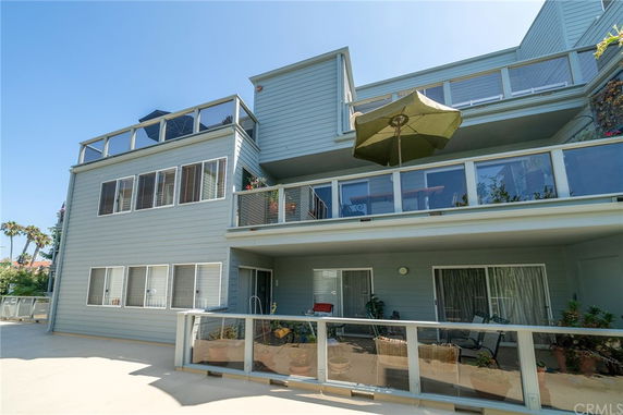 Front view of a multi-story building with balconies and a large umbrella.