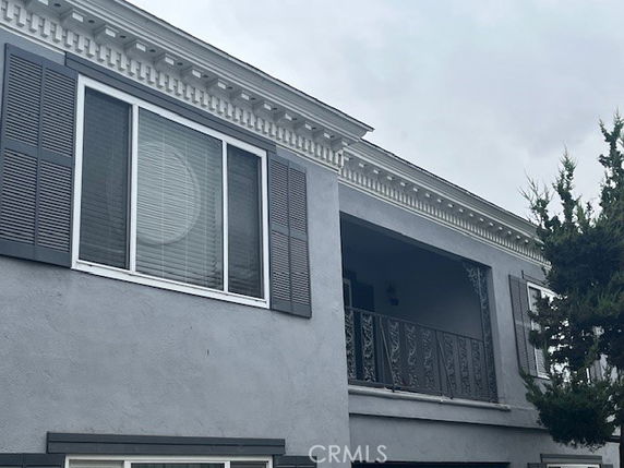 Front view of a two-story building with a balcony and decorative shutters.