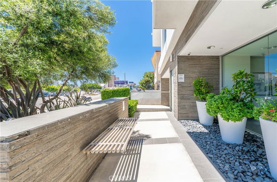 Front view of a modern building entrance with potted plants and a bench.