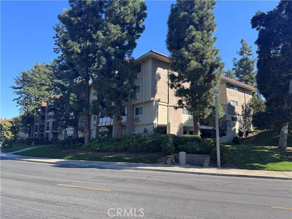 Front view of a multi-story residential building with trees in front.