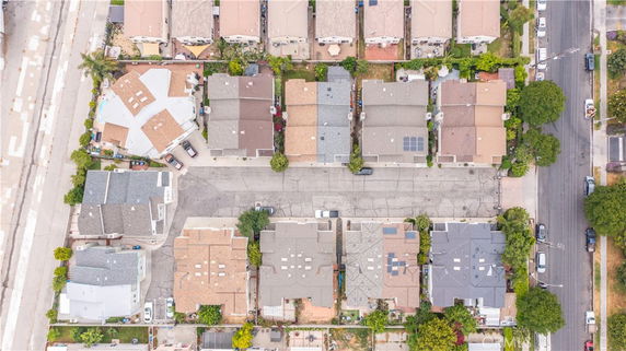 Aerial view of a residential area with multiple houses, showing rooftops with solar panels and a swimming pool.