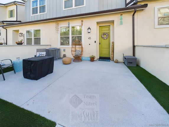 Front view of a townhouse with green door and patio area.