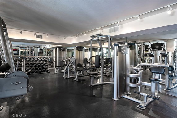 Indoor gym area with various exercise machines and weights.
