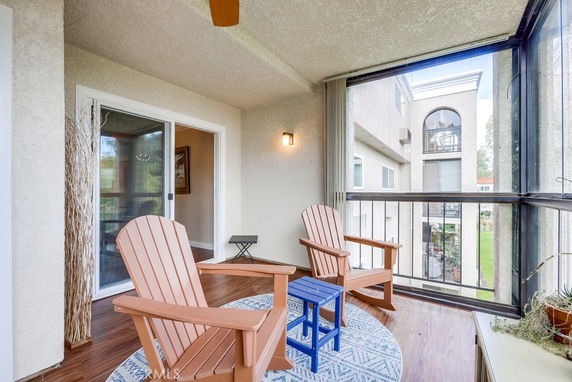 View from a windowed balcony with chairs overlooking nearby buildings.