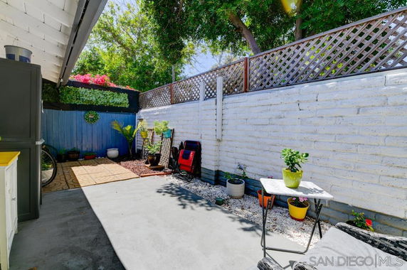 Outdoor area with a white brick wall, plants in pots, and a small table.