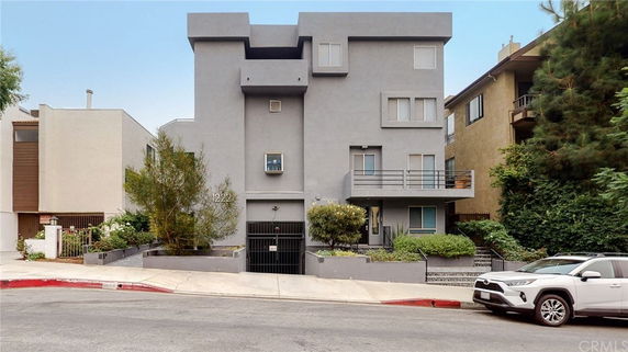 Front view of a multi-story residential building with a grey facade and balconies.