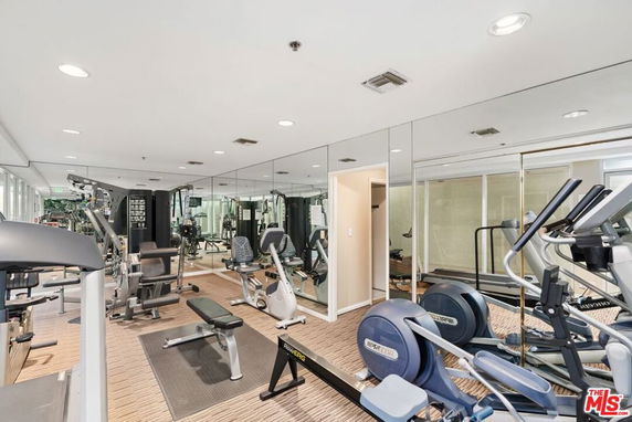 Indoor gym area with various exercise equipment and mirrored walls.