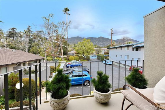 View from a balcony overlooking parking area and mountains in the background.