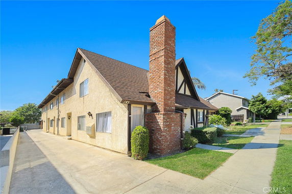 Front view of a two-story residential building with a prominent brick chimney.
