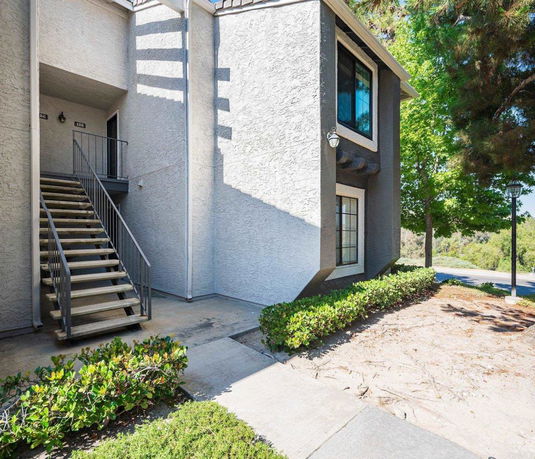 Front view of a building with an exterior staircase leading to the upper floor entrance.