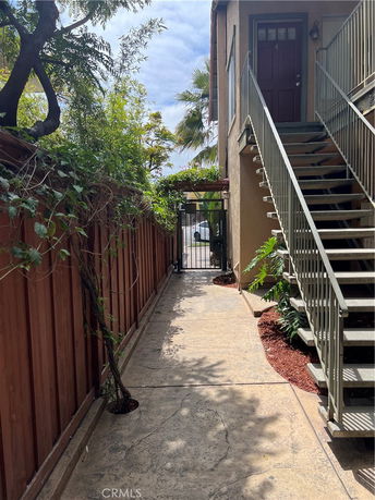 Exterior pathway leading to a staircase and gate next to a building.