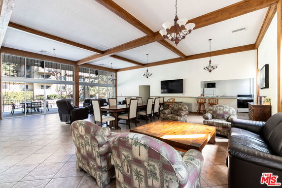 Spacious clubhouse interior with seating area, dining tables, chandeliers, and large windows.
