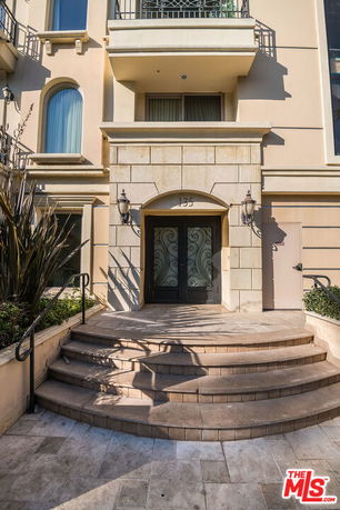Front view of a multi-story building entrance with decorative wrought iron doors and arched windows.